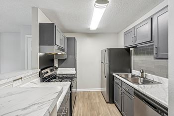 A kitchen with a stove, refrigerator, and cabinets.